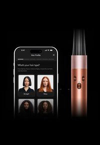 Een stijlvolle haarstylingsapparaat in koper met een gladde afwerking en een zwarte cilinder. Ernaast staat een smartphone waarop haartype-opties worden weergegeven op een donkere achtergrond.