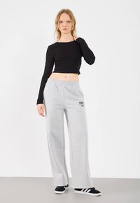 Black long-sleeve cropped top with a round neckline, paired with light gray sweatpants featuring a "TOKYO 1991" print and elastic waistband.