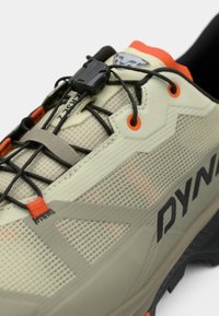 Ελαφρύ αθλητικό παπούτσι για μονοπάτια σε μπεζ χρώμα με πλέγμα, μαύρες κορδόνες, πορτοκαλί λεπτομέρειες και ανθεκτική σόλα; διαθέτει σύστημα ταχείας πρόσδεσης.