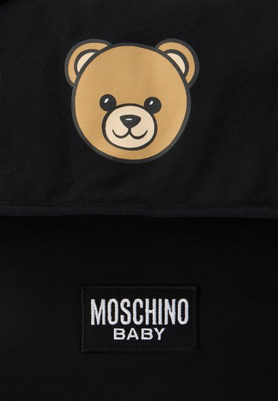 Μαύρο πουκάμισο με γραφικό καφέ αρκούδας με χαμογελαστό πρόσωπο. Το λογότυπο "MOSCHINO BABY" είναι ραμμένο σε λευκό πάνω σε μαύρο κολάρο.