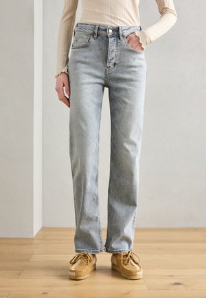 Jeans straight leg in lavaggio chiaro con vita alta, cinque tasche e un leggero effetto sbiadito. Abbinati a scarpe color sabbia con un design testurizzato.