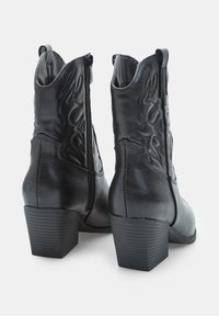 Stivali ankle in pelle nera con chiusura a zip, design testurizzato con motivi di cucitura e tacco medio a blocco.