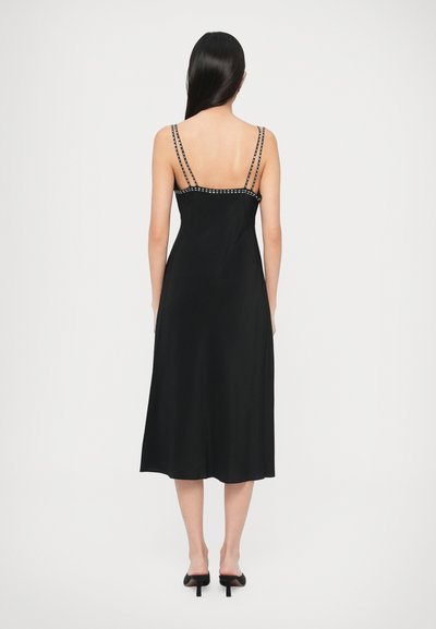 Czarna sukienka midi z satyny na cienkich ramiączkach, z koralikowym zdobieniem na ramionach. Gładka faktura, zwiewny krój i luźna sylwetka.