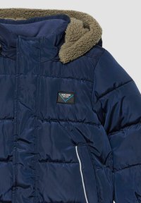Marineblauwe donsjack met een getextureerde olijfgroene fleece-voering in de capuchon, voorzien van een patchlogo en zijzakken met witte biezen.