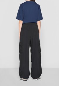 Navy blue t-shirt with a crew neck paired with loose black cargo pants featuring side pockets and elastic waistband.