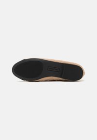 Pantofii slip-on de culoare crem, cu un material texturat, având un model în diamant. Talpa din cauciuc negru are linii de aderență și logo-ul împresionat pe branț.