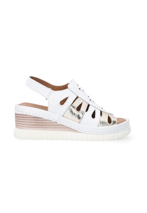 White wedge sandal featuring cut-out design and metallic accents. Textured platform with light pink stripes and a cushioned insole.