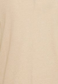 Vaaleanbeige pehmeä tekstuuri kangas, jossa on pystysauma keskellä tekstiil pintaa.