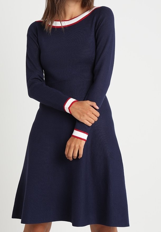 Navy dress with long sleeves, ribbed texture, and contrasting red and white stripes at the collar and cuffs. A-line silhouette.