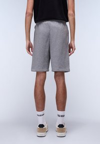 Gray cotton athletic shorts, mid-thigh length, featuring a relaxed fit. Worn with white socks and beige sneakers. Simple, smooth texture.