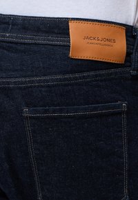 Σκούρο μπλε τζιν από denim με ορατές ραφές στην πίσω τσέπη και καφέ δερμάτινη ετικέτα με την ένδειξη "Jack & Jones Jeans Intelligence."
