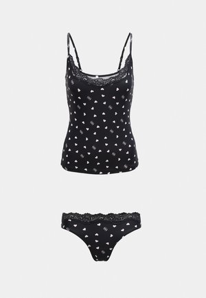 Črna majica s tankimi naramnicami iz spaghetti trakov in ujemajoče se spodnje hlačke, okrašene z rožnatimi srčki in čipkastim robom na belem ozadju.