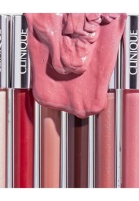 Lip gloss tubes with silver caps in various shades: red, pink, nude, sparkling light pink and a thick, glossy pink swatch on top.
