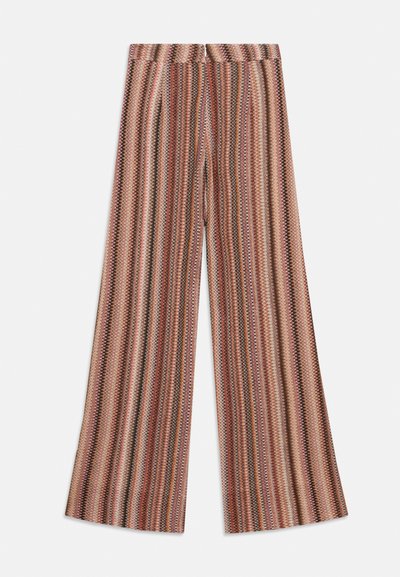 Pantalons larges avec un motif zigzag multicolore dans des nuances de rose, marron et crème sur fond blanc.