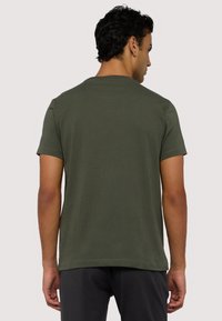 Krátký rukáv, olivově zelené tričko vyrobené z měkké bavlny. Disponuje klasickým výstřihem a volným střihem, s čistým zakončením v pase.