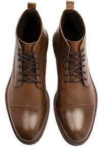 Brązowe skórzane botki za kostkę z wypolerowanym wykończeniem, okrągłym noskiem i ciemnobrązowymi sznurówkami. Posiadają pętelkę przy pięcie i miękką podszewkę.