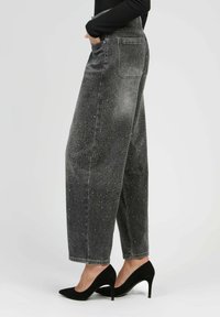 Jean noir taille haute en denim avec une coupe ample, présentant un design délavé et des accents de strass dispersés. Style à cinq poches.