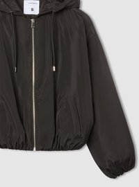 Giacca bomber nera con cappuccio, finitura lucida, chiusura con zip, polsini elasticizzati, due tasche laterali e cordino sul cappuccio. Taglia S.