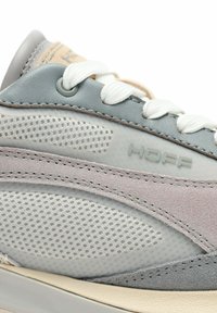 Baskets gris clair avec panneaux en mesh et en daim, lacets blancs et logo "HOFF" embossé. Le design comprend des accents contrastants et une semelle texturée.