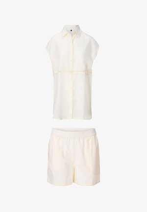 Blouse sans manches crème à boutons avec bordure en dentelle, associée à un short à taille élastique assorti, tous deux en tissu léger.