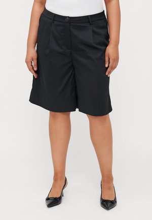 Pantalones cortos negros a medida, fabricados con un material ligero, que cuentan con pinzas en la parte delantera, cierre de botón y un dobladillo ligeramente acampanado.