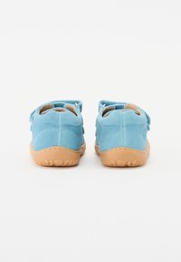 Blå ruskindsko med en tan gummisål og struktureret greb. Har Velcro-remme og en rund tådesign. Bagsiden viser ingen dekorative detaljer.