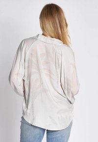 Leichtes, blasses Stoffhemd mit dezentem Palmenblattmuster; verfügt über einen Kragen, eine lockere Passform und lange Ärmel.