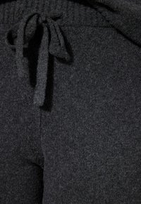 Dunkelgraue Fleece-Jogginghosen mit einer strukturierten Oberfläche, versehen mit einem Kordelzugbund und sichtbaren Nähten.