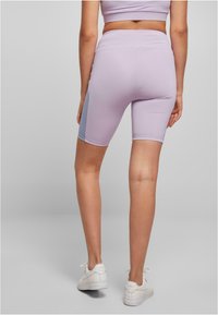 Helle lila Radlerhosen mit hoher Taille, die ein kontrastierendes hellblaues Seitenpanel aufweisen, aus dehnbarem, glattem Stoff gefertigt.