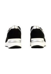 Paire de baskets athlétiques noires et argentées vues de dos, avec des semelles intermédiaires blanches et des détails de fermeture éclair sur les côtés.