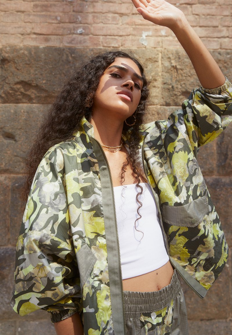 Chaqueta bomber extragrande con estampado floral en verde y amarillo, con cierre de cremallera, puños elásticos y una cinturilla a juego.
