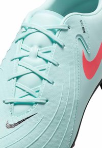 Hele sinine spordijalanõud tekstuuriga pinnaga, roosa Nike swoosh logo ja valged paelad, millel on sooneline disainielement külgedel.