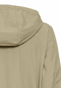 Beige hættejakke i tekstureret stof med et strømlinet design og diskrete syninger på skuldrene og sømmene.