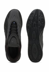 Puma tenisice s crnim sintetičkim gornjim dijelom, teksturiranom završnom obradom, istaknutim logotipom na jeziku i gumene potplate s kružnim žljebovima.
