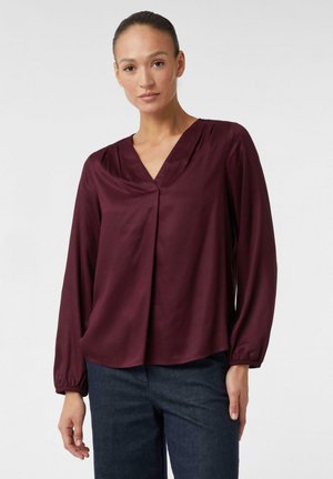 Blusa borgogna con scollatura a V e maniche lunghe a sbuffo. Realizzata in un tessuto morbido con una caduta sottile e una vestibilità rilassata.