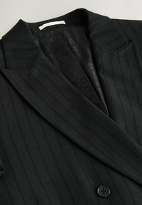 Schwarzer Blazer mit Nadelstreifen, ausgestattet mit einem Reverskragen, einem Ein-Knopf-Verschluss und einem gemusterten Innenfutter. Das Material hat eine glatte Textur.