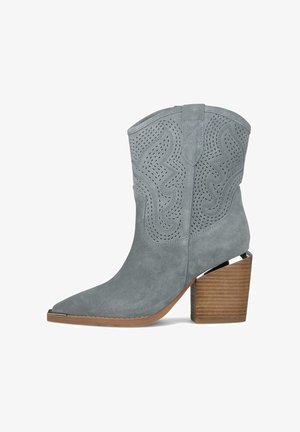 Grijze suède enkellaars met laser-gesneden stiksel, spits toelopende neus, houten blokhak en metalen teenkapdetail.