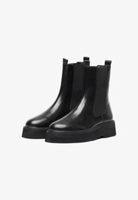 Bottines Chelsea en cuir noir avec panneaux latéraux en élasthanne, bouts ronds et semelles en caoutchouc épais. Texture lisse avec tirettes pour un enfilage plus facile.