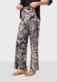 Vida byxor i marinblå och beige mönster, med virvlande blommönster. Tyget ser mjukt ut med en slät yta.