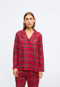 Rødt ternet pyjamas sæt lavet af blødt stof, som har en knapper-up skjorte med en klapkrave og matchende bukser med elastisk talje.