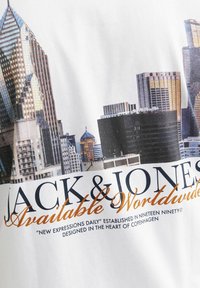 Weißes T-Shirt mit einem Grafikdruck einer Stadtsilhouette, mit dem Text "JACK & JONES Weltweit verfügbar" in schwarzer und orangefarbener Schrift.