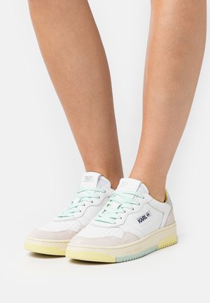 Baskets blanches en cuir avec des lacets vert menthe, des accents en suède beige et une semelle jaune pastel. Présente un logo sur le côté et un détail perforé sur le bout.
