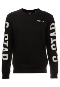 Černá mikina vyrobená z bavlny, s dlouhými rukávy a velkým bílým nápisem "G-STAR RAW" na obou rukávech a malým logem na hrudi.