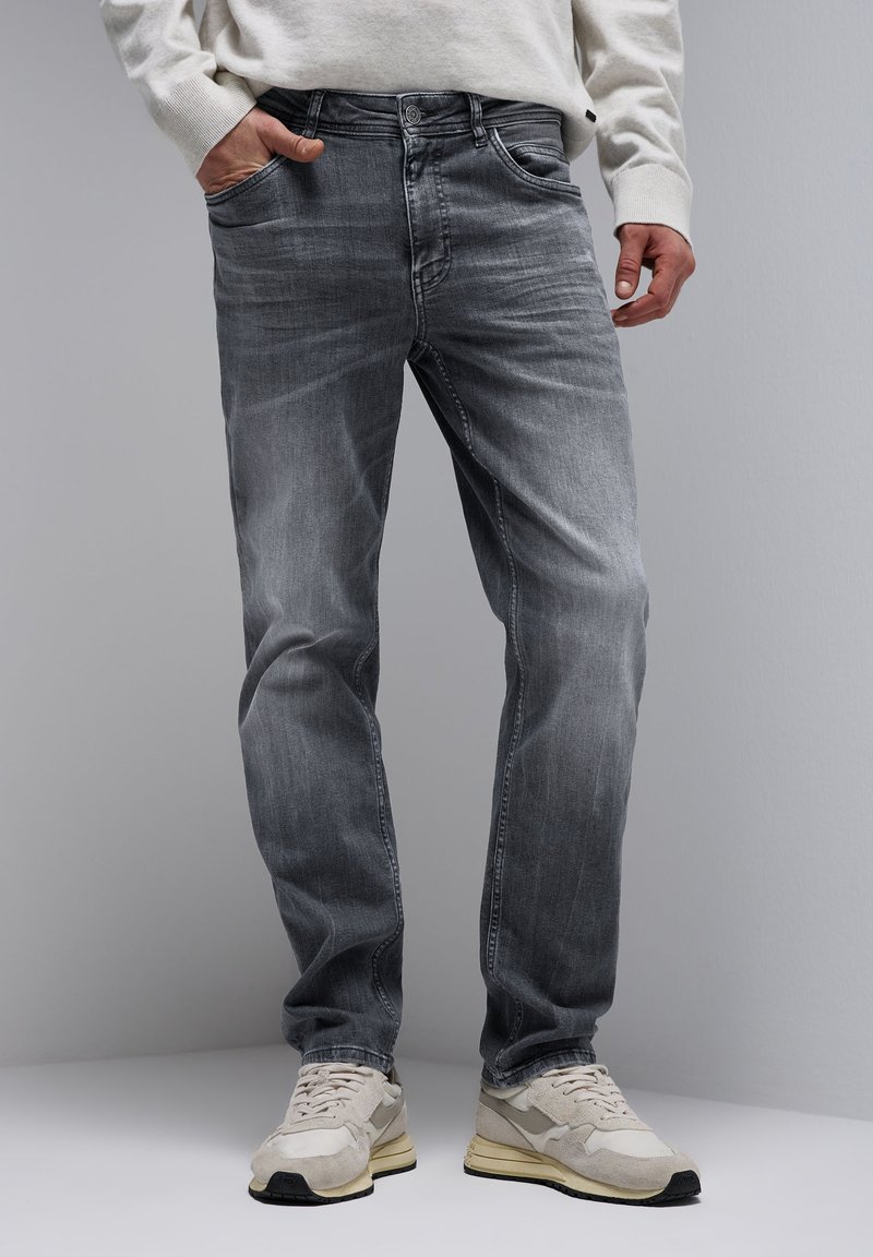 Grijze denim jeans met een recht model, subtiele vervaging en vijf zakken, gecombineerd met lichtgekleurde sneakers.