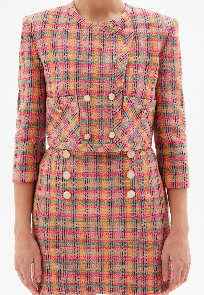 Ensemble veste et jupe ajustée à carreaux rose, orange et verte, avec boutons dorés, manches trois-quarts et poches à rabat devant.