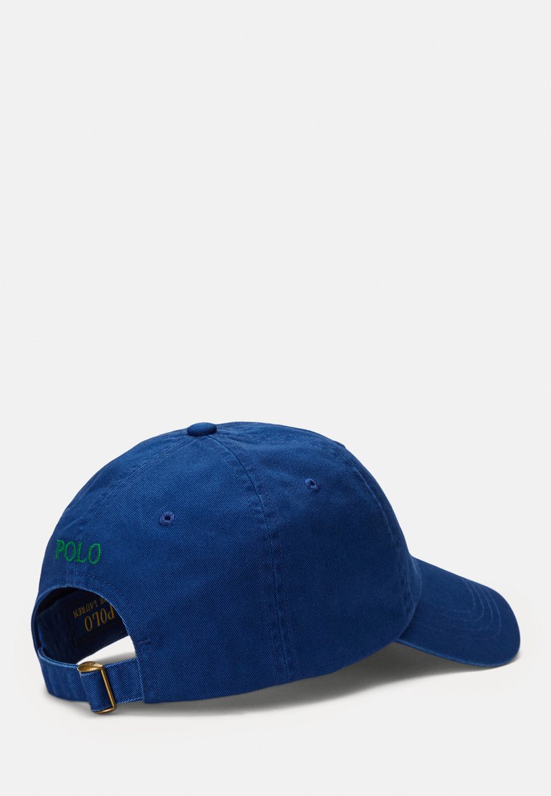 Casquette de baseball en coton bleu avec un bord incurvé, une sangle réglable et une broderie verte "POLO" à l'arrière. Texture lisse, design décontracté.