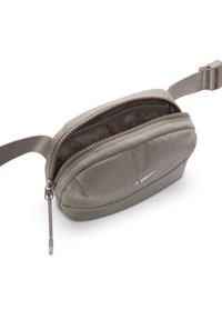 Ljusgrå tygpåse med dragkedja, mesh-inredning och en liten silverlogotyp. Har en rem för enkel bärbarhet.