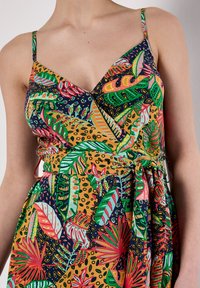 Farbenfrohes Kleid mit einem lebhaften tropischen Muster aus Blättern und Blumen in den Farben Grün, Pink und Orange, tailliert.