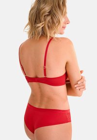 Ensemble de bikini rouge comprenant un soutien-gorge à fines bretelles avec ajustement et un bas taille basse assorti, tous deux fabriqués en tissu lisse et extensible.