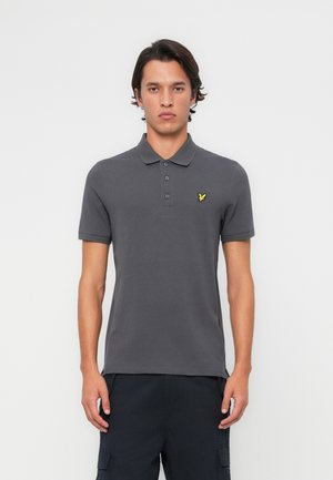 Polo gris en coton, avec un col, une patte de boutonnage à trois boutons, des manches courtes et un logo brodé jaune sur la poitrine.